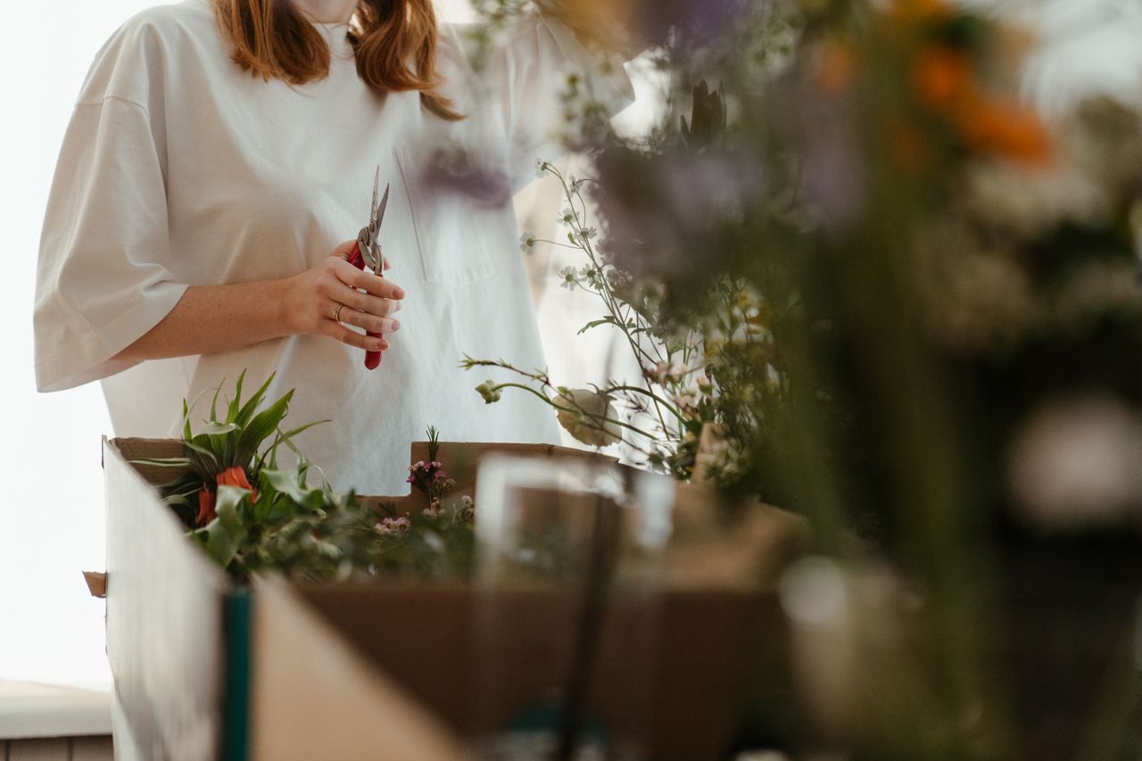 Mastering the First Impression: Your intriguing post title goes here Woman arranging fresh flowers using scissors indoors. Perfect for floral arrangement and gardening themes.