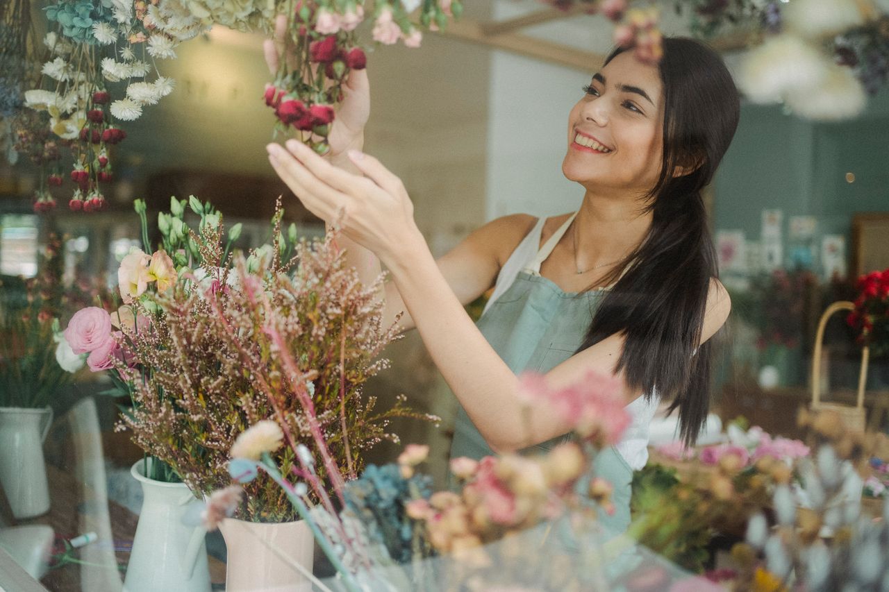 The Art of Drawing Readers In: Your attractive post title goes here Smiling female florist in apron standing near table with flowers and making bouquets in floral shop